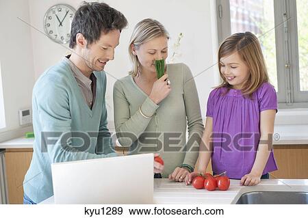 Stock Photo - Family cooking with the recipe on a laptop. Fotosearch