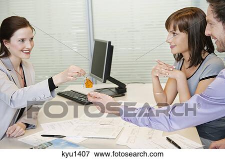 Female real estate agent giving house keys to a couple View Large Photo Image Stock Photo - Female real estate agent giving house keys to a couple. Fotosearch