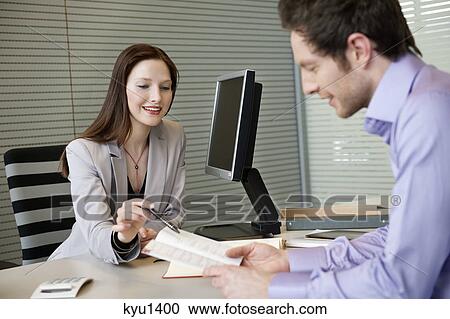 Female real estate agent showing a brochure to a man View Large Photo Image Stock Image - Female real estate agent showing a brochure to a man. Fotosearch