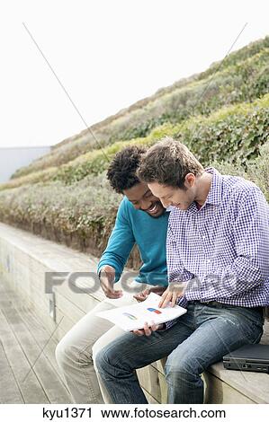 Friends discussing documents on a boardwalk View Large Photo Image Stock Image - Friends discussing documents on a boardwalk. Fotosearch