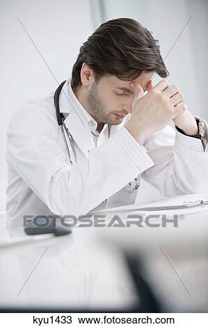 Male doctor sitting in his office and looking upset View Large Photo Image Stock Image - Male doctor sitting in his office and looking upset. Fotosearch