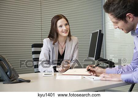 Man signing documents with a female real estate agent sitting in front of him View Large Photo Image Stock Image - Man signing documents with a female real estate agent sitting in front of him. Fotosearch