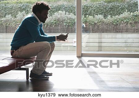 Stock Photo - Man text messaging on a mobile phone. Fotosearch