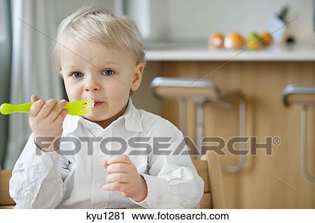 Stock Image - Portrait of a boy eating with a fork. Fotosearch