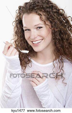 Stock Photo - Portrait of a woman eating yogurt. Fotosearch