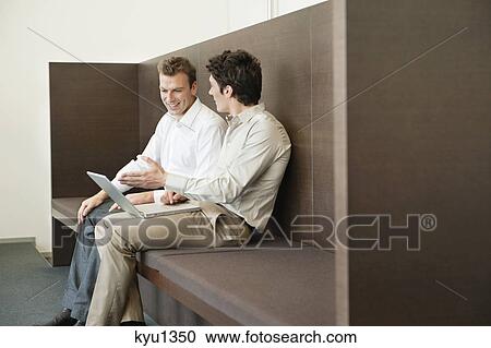 Stock Image - Two businessmen working in an office. Fotosearch