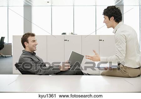 Stock Image - Two businessmen working in an office. Fotosearch