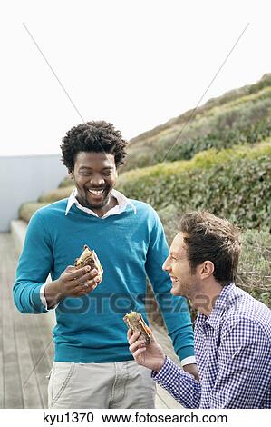 Two friends eating sandwiches on a boardwalk View Large Photo Image Stock Image - Two friends eating sandwiches on a boardwalk. Fotosearch