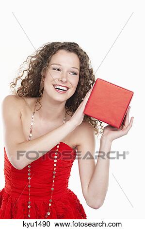 Woman holding a present near her ear View Large Photo Image Stock Image - Woman holding a present near her ear. Fotosearch