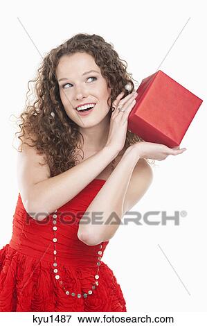 Woman holding a present near her ear View Large Photo Image Stock Photo - Woman holding a present near her ear. Fotosearch