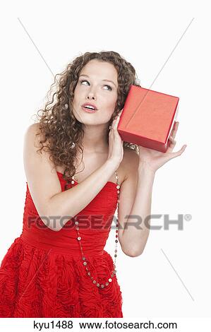 Woman holding a present near her ear View Large Photo Image Stock Photo - Woman holding a present near her ear. Fotosearch