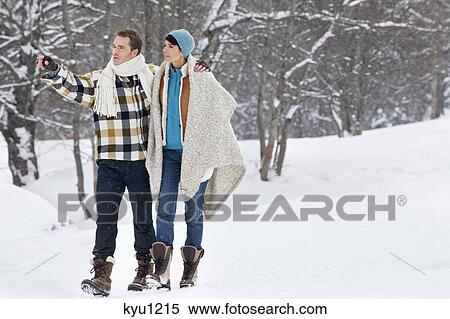 Stock Photography - Young couple embracing, walking in snow. Fotosearch