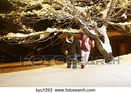 Young couple holding candles, walking in snow by night View Large Photo Image Stock Image - Young couple holding candles, walking in snow by night. Fotosearch