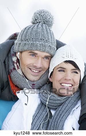 Stock Photo - Young couple in winter clothes, listening to music together. Fotosearch