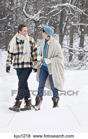 Stock Photo - Young couple looking at each other, walking in snow. Fotosearch