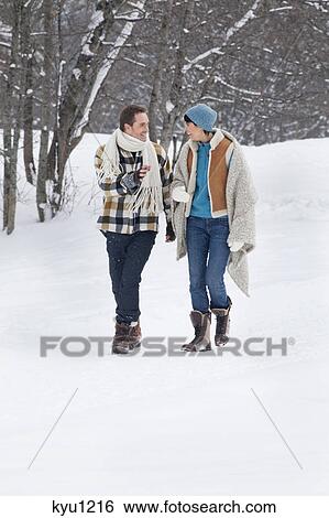Stock Photograph - Young couple looking at each other, walking in snow. Fotosearch