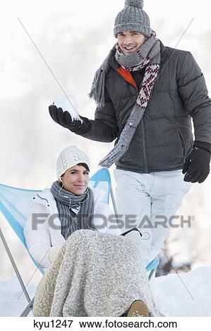 Young man about to throw snowball at woman resting View Large Photo Image Stock Photo - Young man about to throw snowball at woman resting. Fotosearch