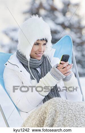 Young woman using mobile phone in snow View Large Photo Image Stock Image - Young woman using mobile phone in snow. Fotosearch