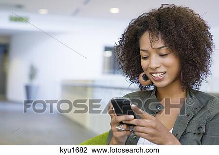 Stock Image - African American woman using mobile phone in university. Fotosearch