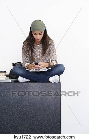 Stock Image - Beautiful woman using a mobile phone against white background. Fotosearch