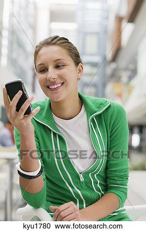 Stock Image - Beautiful woman using mobile phone in university lobby. Fotosearch