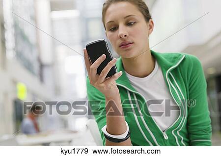 Stock Photo - Beautiful woman using mobile phone in university lobby. Fotosearch
