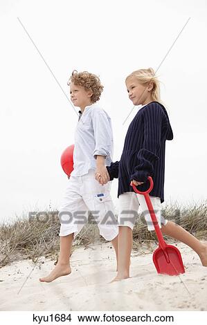 Brother and his sister walking on sand, holding hands View Large Photo Image Picture - Brother and his sister walking on sand, holding hands. Fotosearch