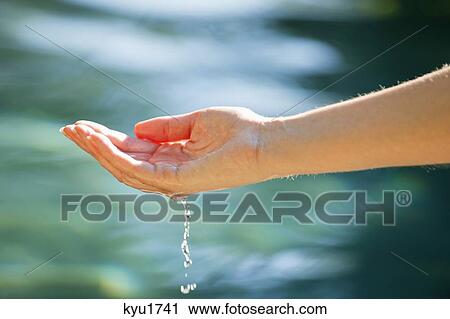 Stock Image - Close-up of a man's hand touching the water of the swimming pool. Fotosearch