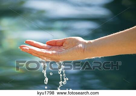 Stock Photo - Close-up of a man's hand touching the water of the swimming pool. Fotosearch