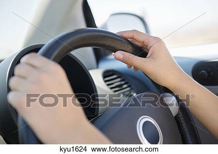 Picture - Close-up of a young woman's hand holding steering wheel. Fotosearch