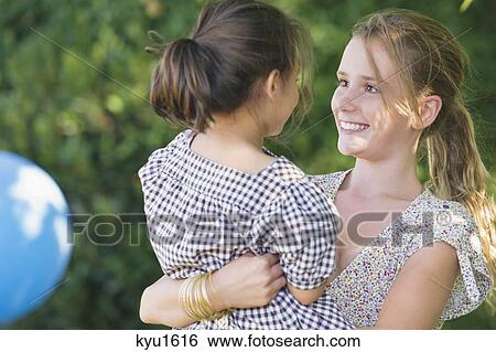 Cute girl carrying little sister and smiling View Large Photo Image Stock Photograph - Cute girl carrying little sister and smiling. Fotosearch