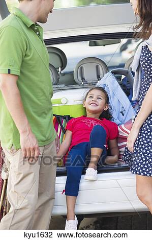Cute little girl lying in car trunk while parents looking at her View Large Photo Image Stock Image - Cute little girl lying in car trunk while parents looking at her. Fotosearch