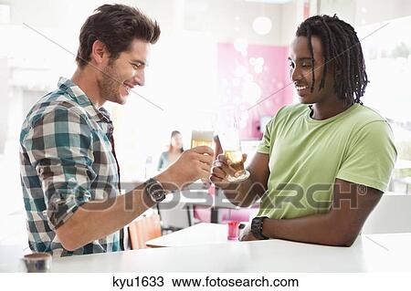 Stock Image - Friends toasting beer at a bar. Fotosearch