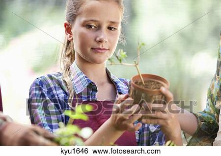 Girl holding a potted plant View Large Photo Image Stock Photograph - Girl holding a potted plant. Fotosearch