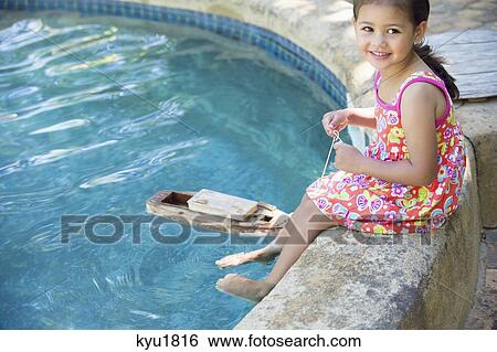 Girl sitting at edge of swimming pool with toy boat in water View Large Photo Image Stock Photograph - Girl sitting at edge of swimming pool with toy boat in water. Fotosearch