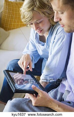 Stock Photo - Man and a little boy looking at digital tablet. Fotosearch