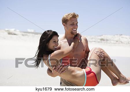 Man carrying woman on the beach View Large Photo Image Stock Photo - Man carrying woman on the beach. Fotosearch