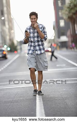 Stock Photography - Man talking on a mobile phone while walking on the road. Fotosearch