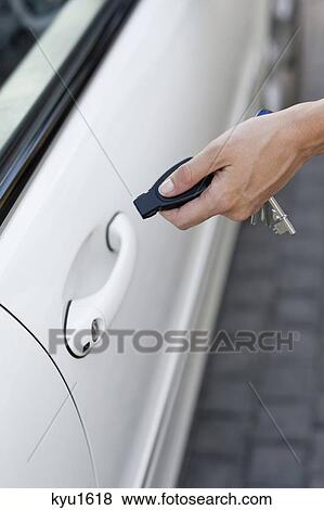 Person's hand unlocking the car with remote control View Large Photo Image Stock Photo - Person's hand unlocking the car with remote control. Fotosearch