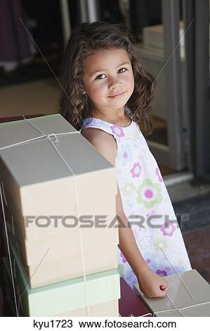 Stock Image - Portrait of a cute little girl standing by the stack of objects. Fotosearch