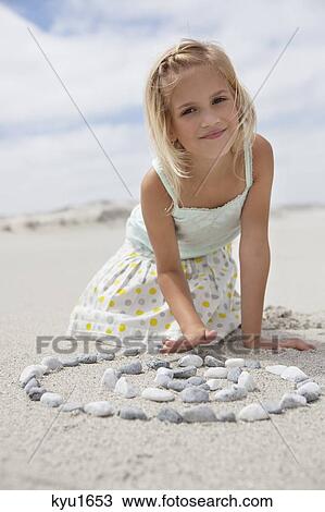 Portrait of a girl playing with pebbles on beach View Large Photo Image Stock Image - Portrait of a girl playing with pebbles on beach. Fotosearch