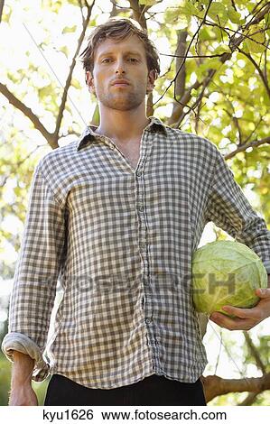 Stock Photograph - Portrait of a man holding a cabbage. Fotosearch