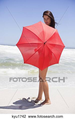 Portrait of a woman holding an umbrella on the beach View Large Photo Image Stock Image - Portrait of a woman holding an umbrella on the beach. Fotosearch