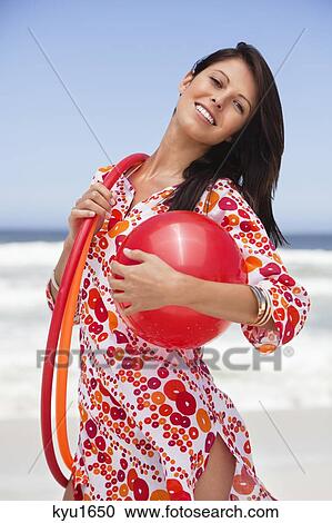 Stock Image - Portrait of a young woman carrying ball and plastic hoops. Fotosearch