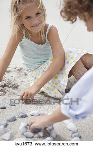 Siblings playing with pebbles on beach View Large Photo Image Stock Image - Siblings playing with pebbles on beach. Fotosearch