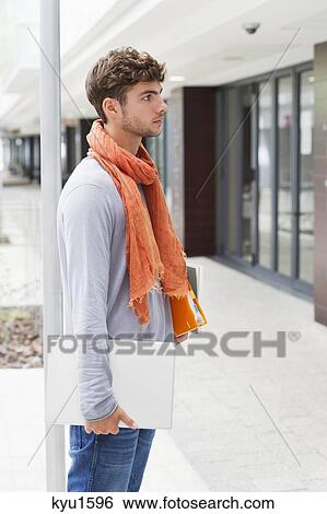 Side profile of a man standing with books and laptop in hands View Large Photo Image Stock Photograph - Side profile of a man standing with books and laptop in hands. Fotosearch