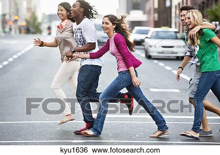 Stock Photograph - Smiling friends crossing the road. Fotosearch