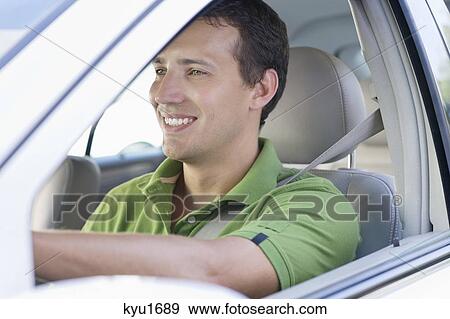 Smiling mid adult man driving a car View Large Photo Image Stock Photo - Smiling mid adult man driving a car. Fotosearch