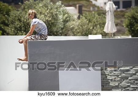Stock Photo - Teenage boy sitting at the edge of a terrace. Fotosearch