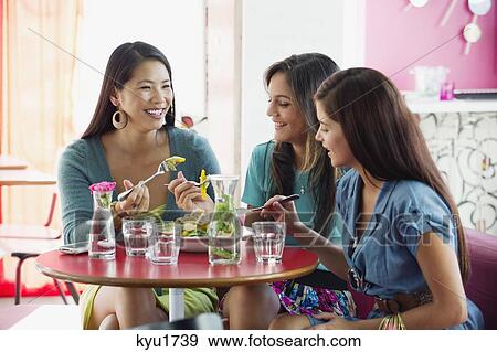 Stock Photo - Three women eating food in a restaurant. Fotosearch
